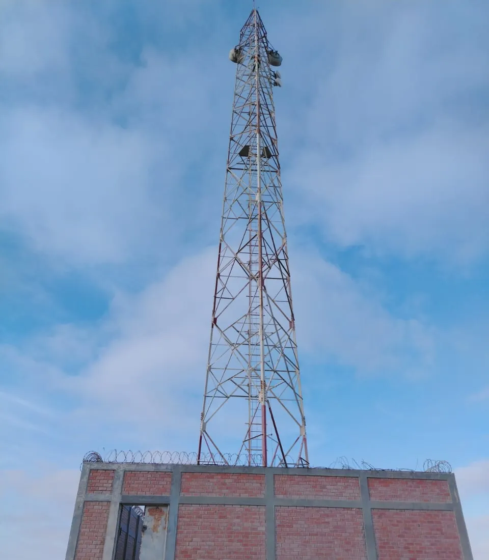 Torre de telecomunicaciones levantada sobre una edificación de ladrillo.