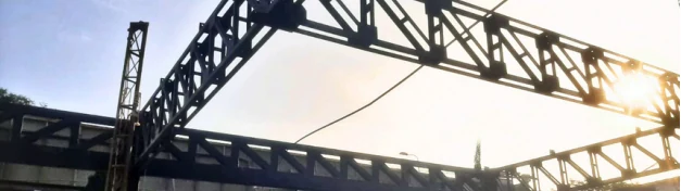 Armaduras metálicas de un techo autosoportado vistas desde abajo, a contraluz.
